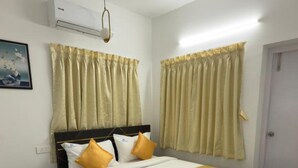 A bedroom with a bed, a nightstand, an air conditioning unit, and a door.