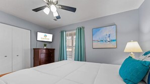 A bedroom with a bed, a ceiling fan, a TV, a painting, and a dresser. - Scenic Cottage at Fall Creek (Branson)