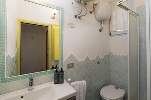 Ein Badezimmer mit Waschbecken, Spiegel, Toilette und Dusche.