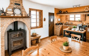 A rustic kitchen with a brick fireplace, wooden cabinets, and a dining area with a wooden table and chairs. - Gorgeous home in Pizarra with private swimming pool, can be inside or outside (Pizarra)