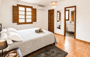 A bedroom with a bed, a bedside table, a lamp, a mirror, and a window with shutters. - Awesome home in Pizarra with private swimming pool, can be inside or outside (Pizarra)
