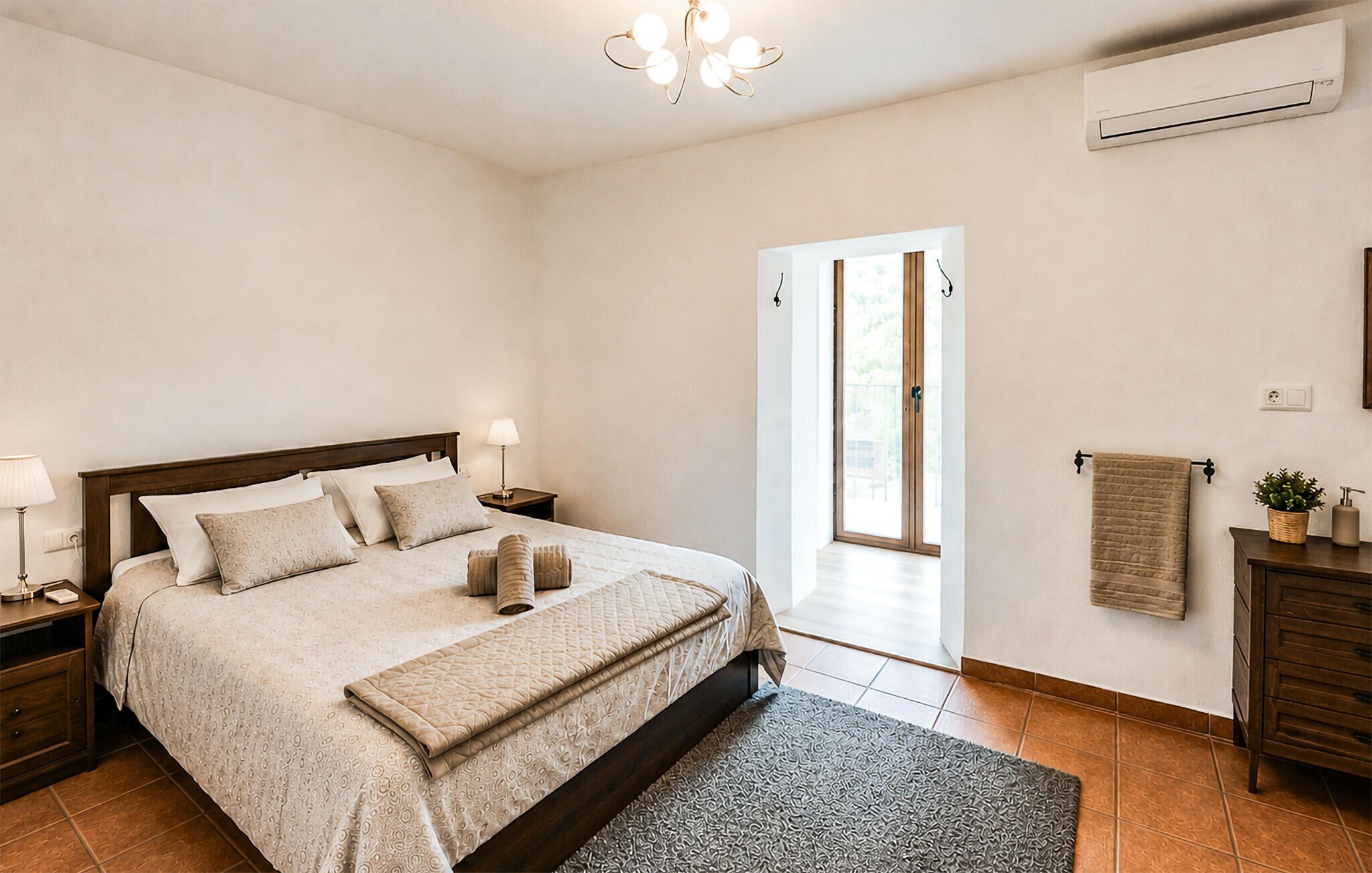Une chambre à coucher comprenant un lit, des tables de chevet, une lampe, un climatiseur, une fenêtre et une porte.