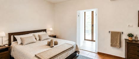 Une chambre à coucher comprenant un lit, des tables de chevet, une lampe, un climatiseur, une fenêtre et une porte.