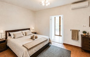 A bedroom with a bed, bedside tables, a lamp, an air conditioner, a window, and a door. - Gorgeous home in Pizarra with private swimming pool, can be inside or outside (Pizarra)
