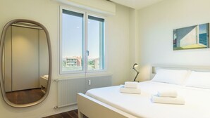 Ett hotellrum med en säng, ett stort fönster, ett element och en tavla på väggen.