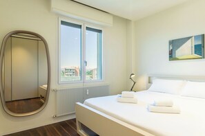 A hotel room with a bed, a large window, a radiator, and a painting on the wall. - Apartment in Milan with 2 bedrooms sleeps 4 (Milan)