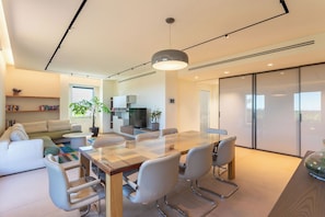 A modern living room with a glass-top dining table, white sofas, and a kitchen area with a TV. - Apartment in Milan with 2 bedrooms sleeps 4 (Milan)