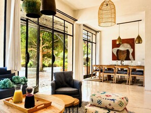 A spacious living area with large windows, a dining set, and a cozy seating arrangement. - Palais Idalya (Essaouira)