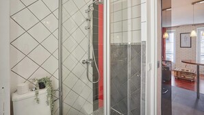 Ein modernes Badezimmer mit Duschkabine aus Glas, weißen Fliesen und sichtbarer Toilette.