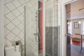 Ein modernes Badezimmer mit Duschkabine aus Glas, weißen Fliesen und sichtbarer Toilette.