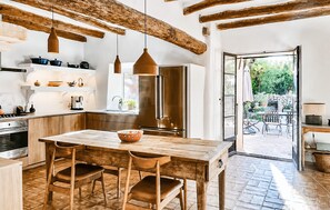 Eine moderne Küche mit Holzbalken, einem Edelstahlkühlschrank und einem Essbereich mit Holztisch und -stühlen.