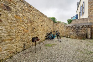 Eine Steinsäule, ein Fahrrad und ein kleiner Tisch in einem Innenhof.