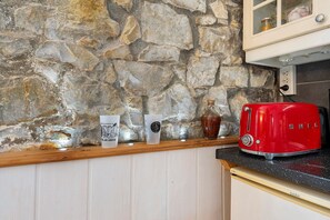 A kitchen with a stone wall, wooden countertop, and a red toaster. - Apartment 'Centre Crozon' with Wi-Fi (Crozon)