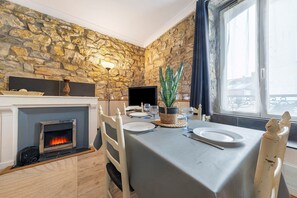 Ein Essbereich mit Steinwand, Kamin, Tisch für zwei Personen und einem Fenster mit Blick.