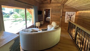 En stuga byggd av timmer med en böjd soffa, ett träräcke och en målning av ett rådjur.