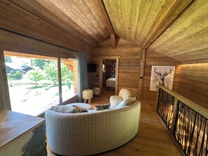 Ein Blockhaus-Interieur mit einer gebogenen Couch, einem Holzbalken und einem Bild von einem Reh.