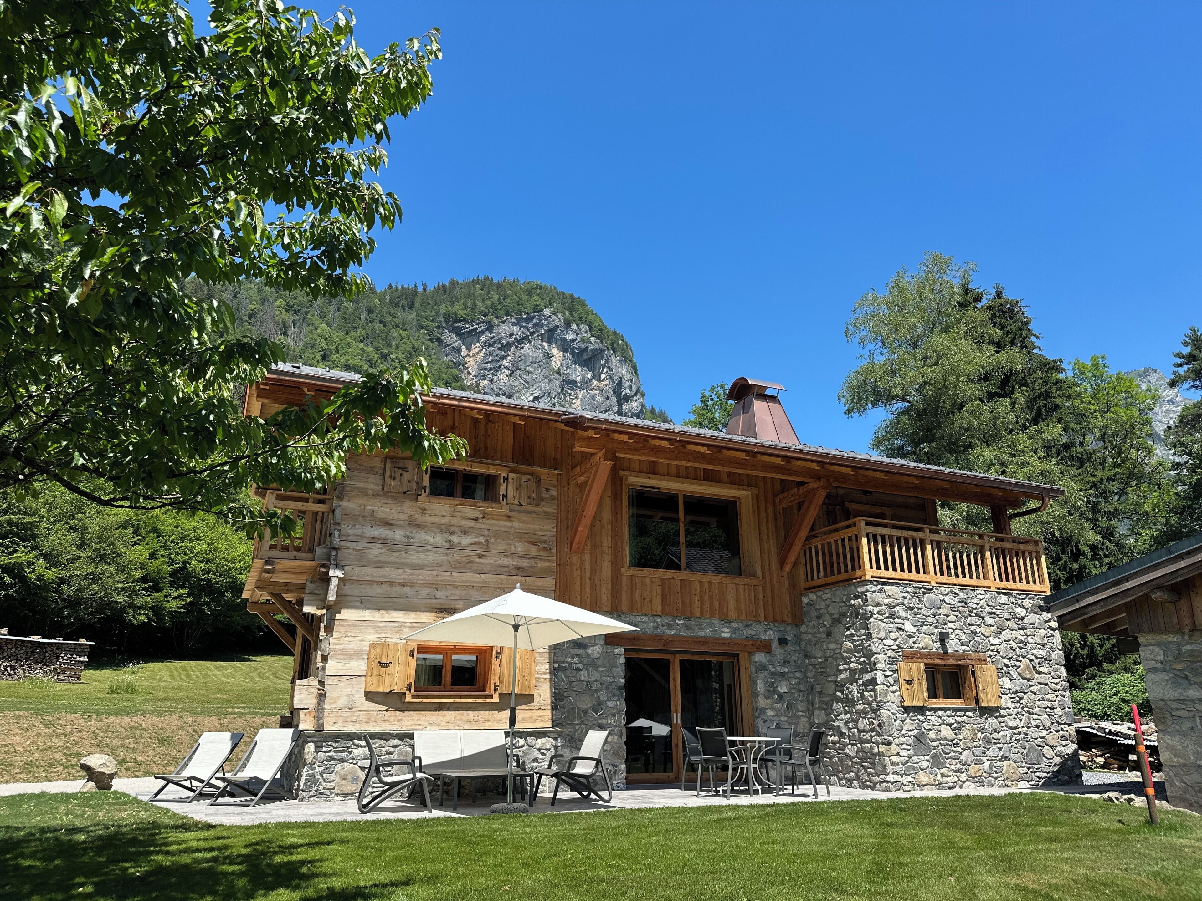 Eine Holzhütte mit Steinwänden, einem Balkon und Sitzgelegenheiten im Freien.