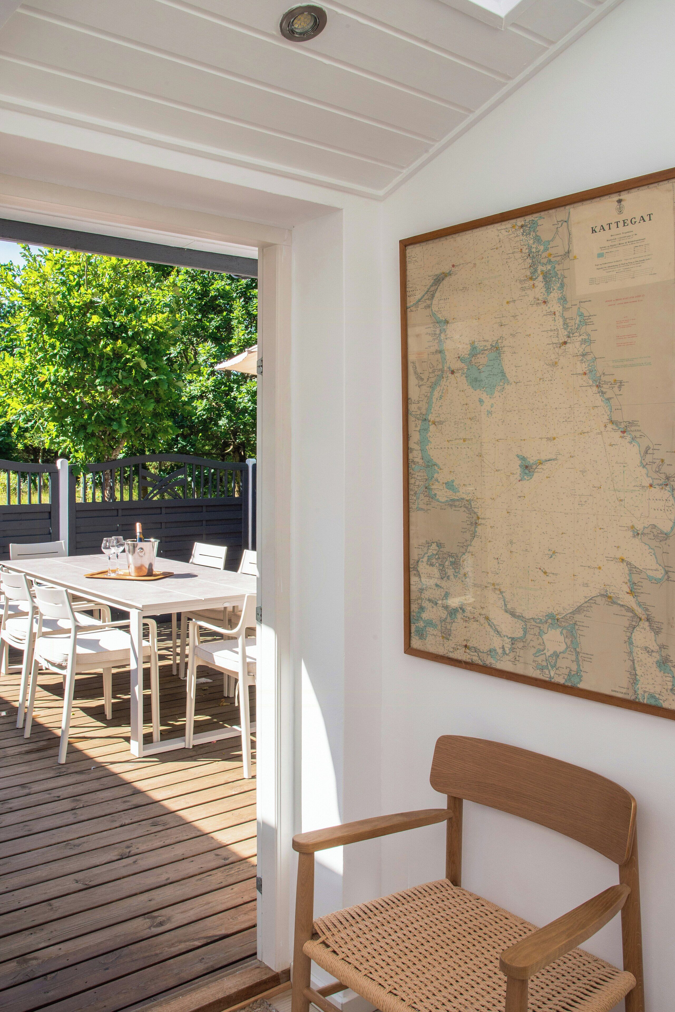 A dining area with a table and chairs, a wooden deck, and a map on the wall.