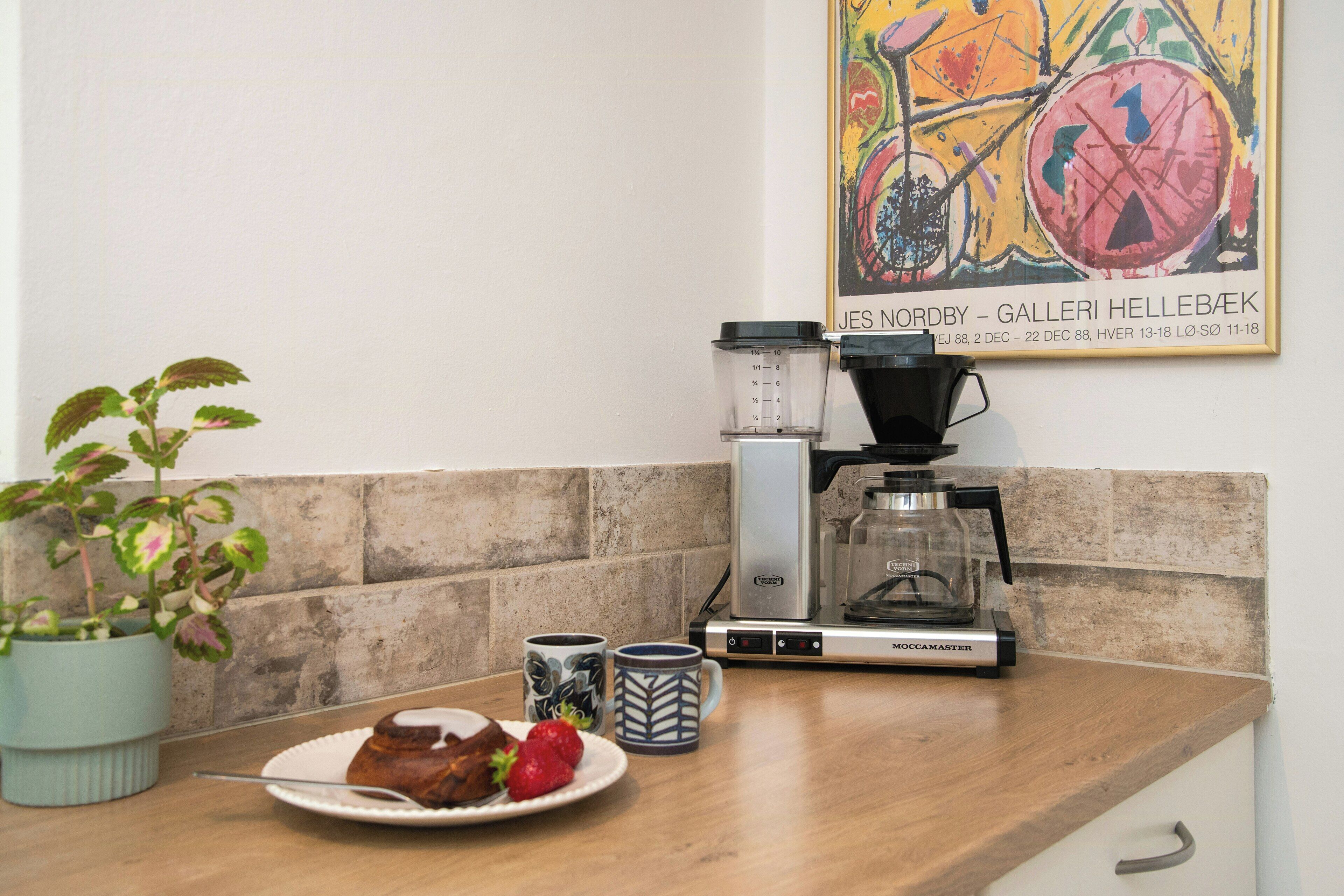 Un comptoir de cuisine avec une machine à café, une balance et une assiette contenant de la nourriture.