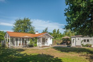 A residential property with a covered patio, a fenced garden, and a small outdoor seating area. - Retro home with three terraces near the beach (Glesborg)