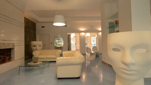 A modern interior with a white sofa, a glass coffee table, and a large abstract sculpture. - TUAREG Hotel (Maruggio)