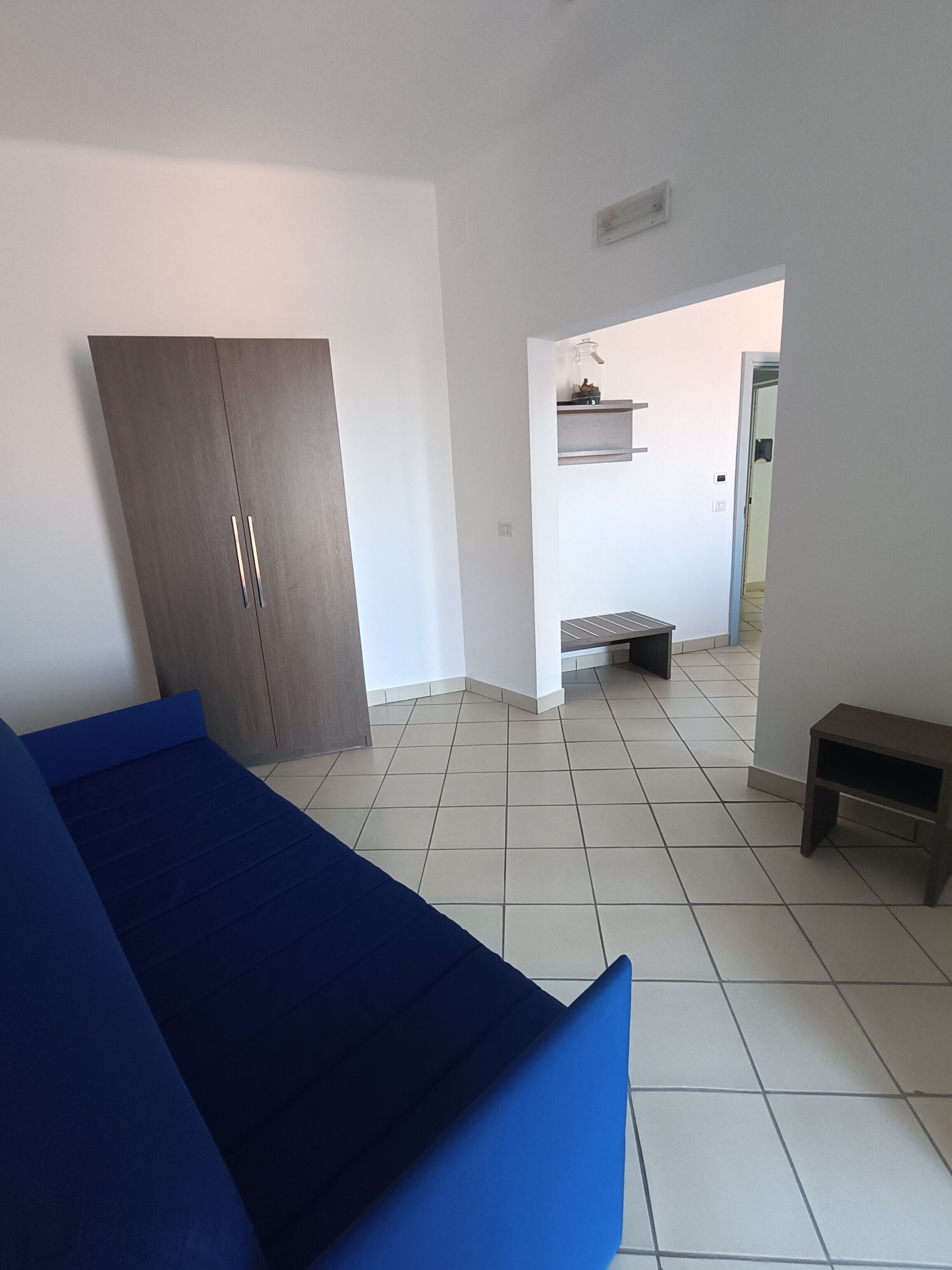 Een kamer met een bed, een kledingkast, een tafeltje en een bank.