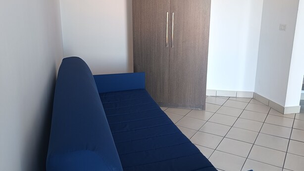 Quarto com cama, guarda-roupa e chão em azulejos.