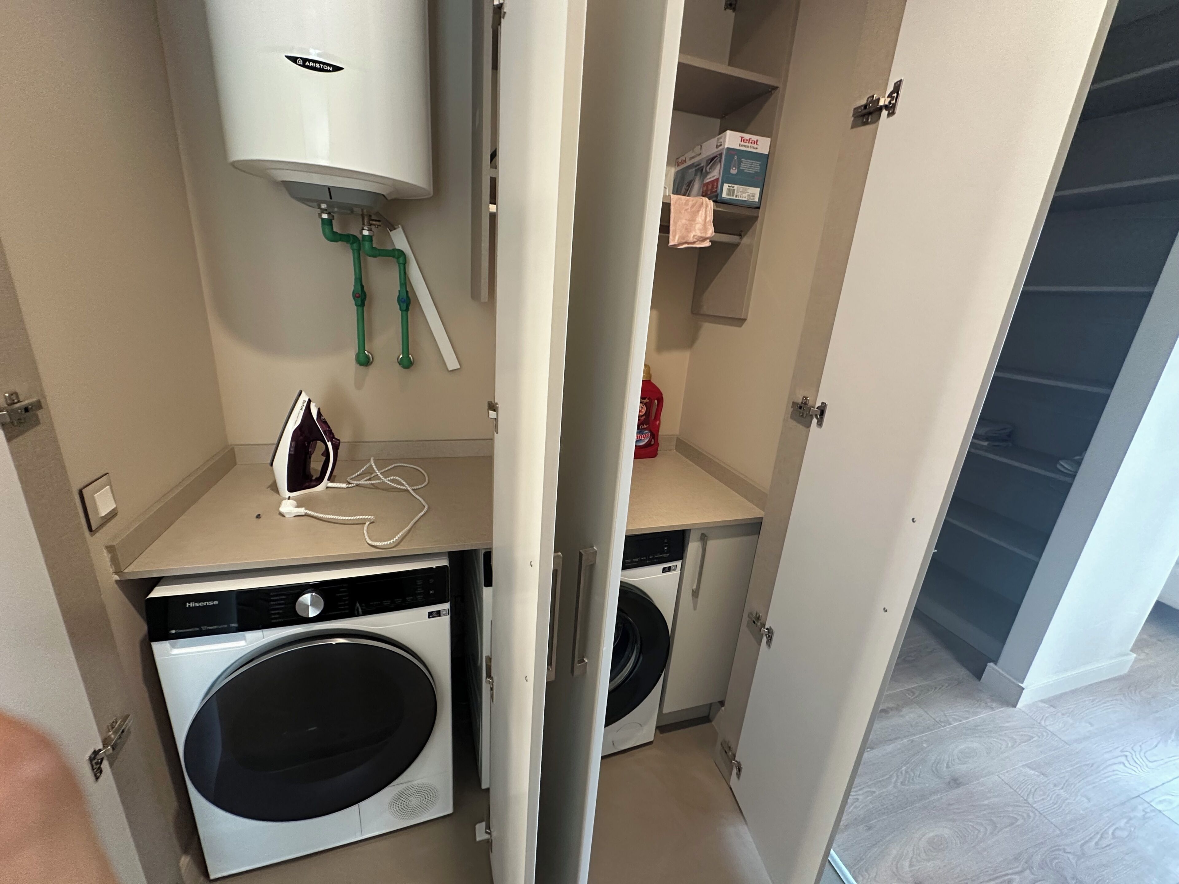 A compact laundry room with a washing machine, dryer, and a water heater.