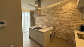 Una cocina moderna con pared de piedra, una isla central y horno empotrado.