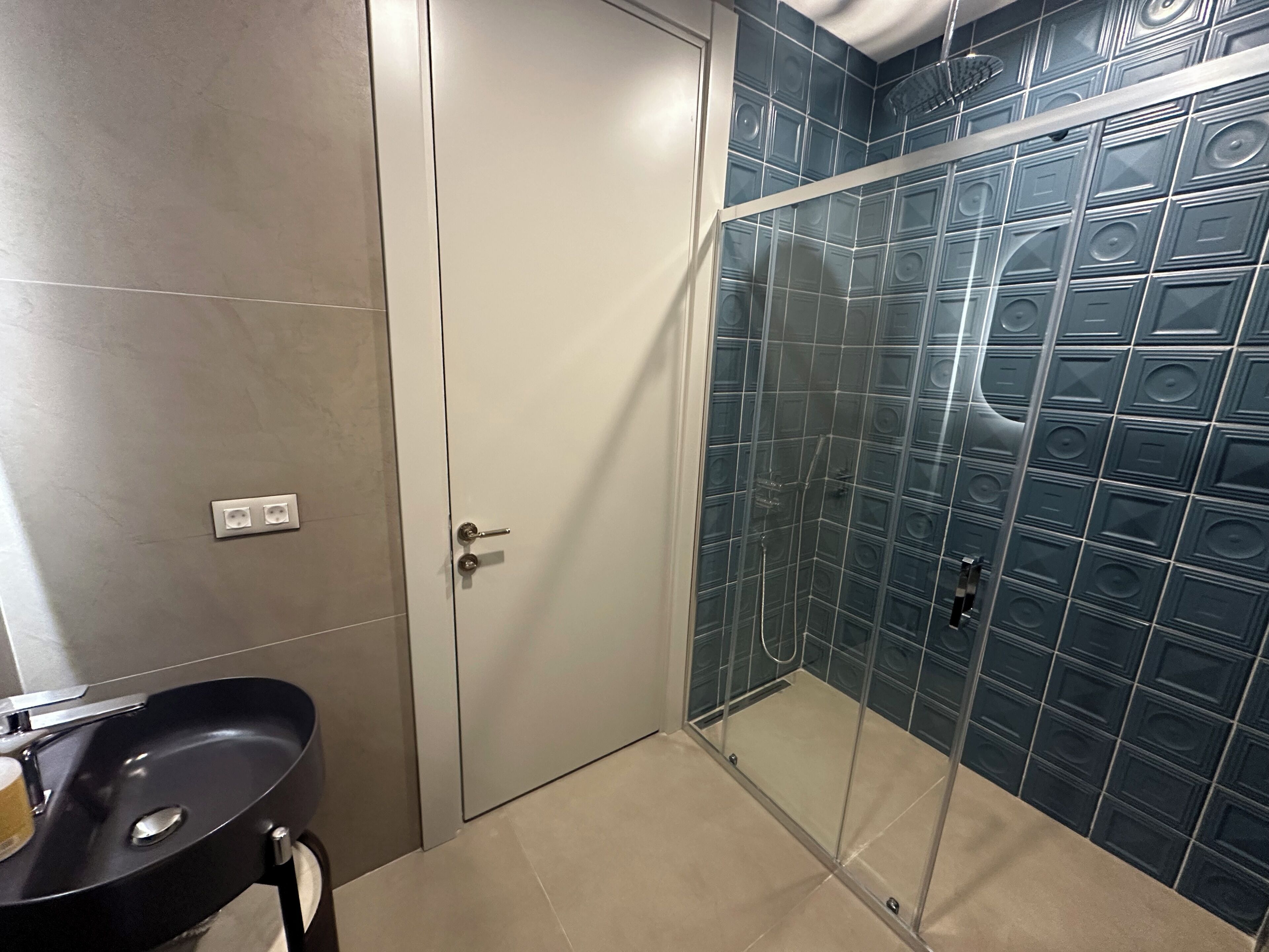Un baño con ducha, lavamanos y una puerta.