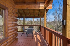 A wooden cabin with a covered porch, a table, and chairs. - Morning Glory (Sevierville)