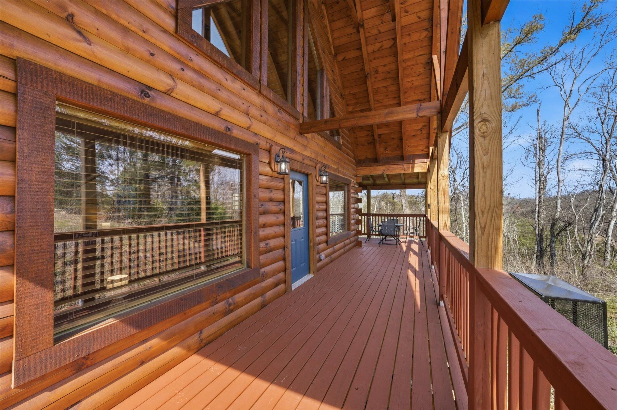 A log cabin with a wooden deck, large windows, and a door.