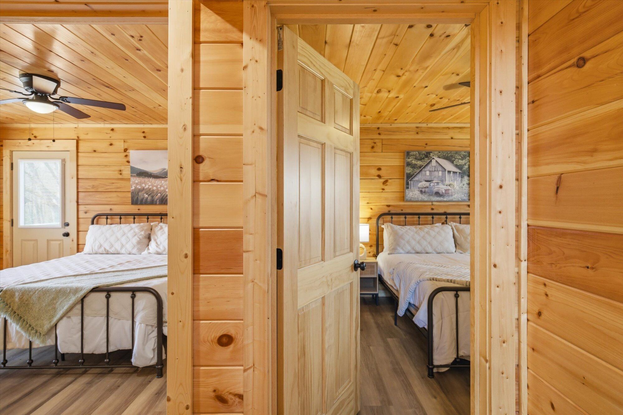 A wooden cabin with two beds, a ceiling fan, and wooden walls.