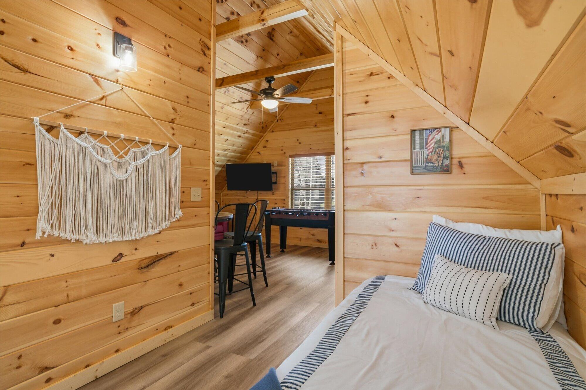 Interior acogedor de una cabaña de madera con cama, escritorio y ventilador de techo.
