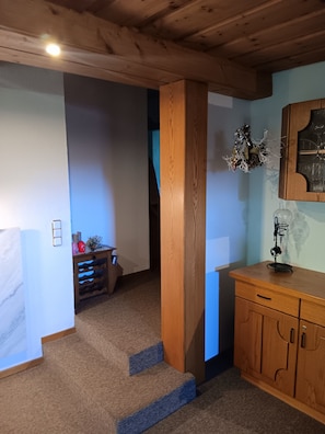 Escada de madeira que leva a um quarto com um armário de madeira e um objeto decorativo na parede.