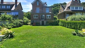 A two-story house with a well-maintained lawn and a small garden area.