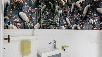 A bathroom with a white tiled wall, a mirror, a sink with a faucet, and a towel rack.