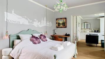 Een slaapkamer met een bed, een bureau, een stoel, een spiegel en stadsgezicht kunst aan de muur.