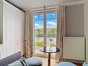 Une pièce avec vue sur un lac, une table ronde avec un vase et un radiateur.