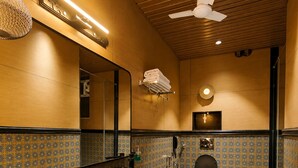 A modern bathroom with a large mirror, a black sink, a toilet, and patterned tiles. - The Luxury Tiger at Lake Pichola (Udaipur)