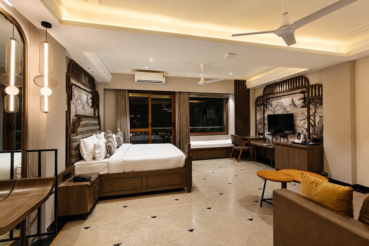 A hotel room with a bed, desk, chair, and a TV.