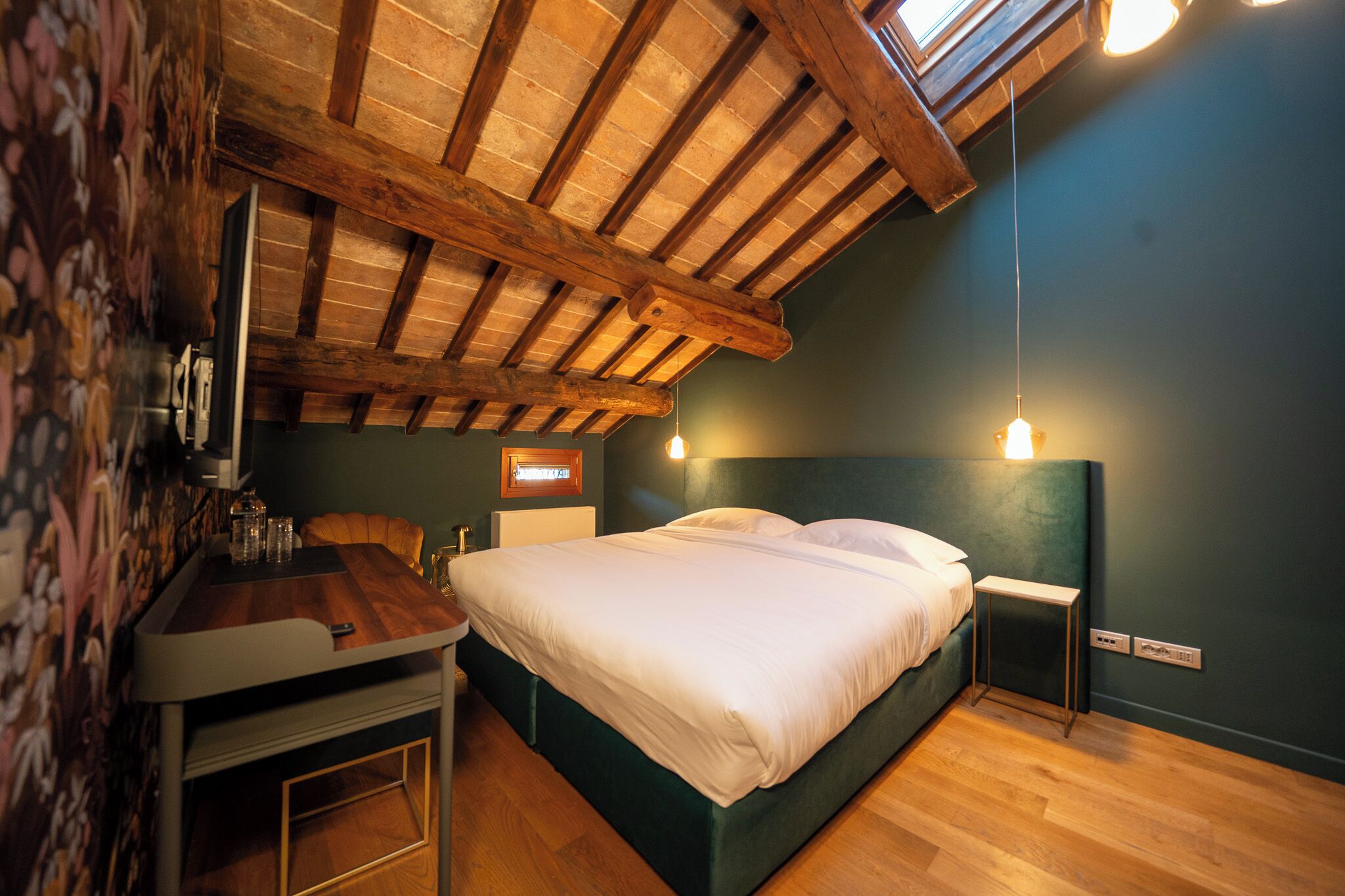 Une chambre avec un plafond en bois, un lit, des tables de chevet et une petite table avec des verres.
