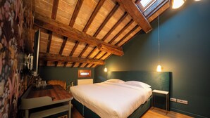 Un dormitorio con techo de madera, una cama, mesitas de noche y una pequeña mesa con vasos.