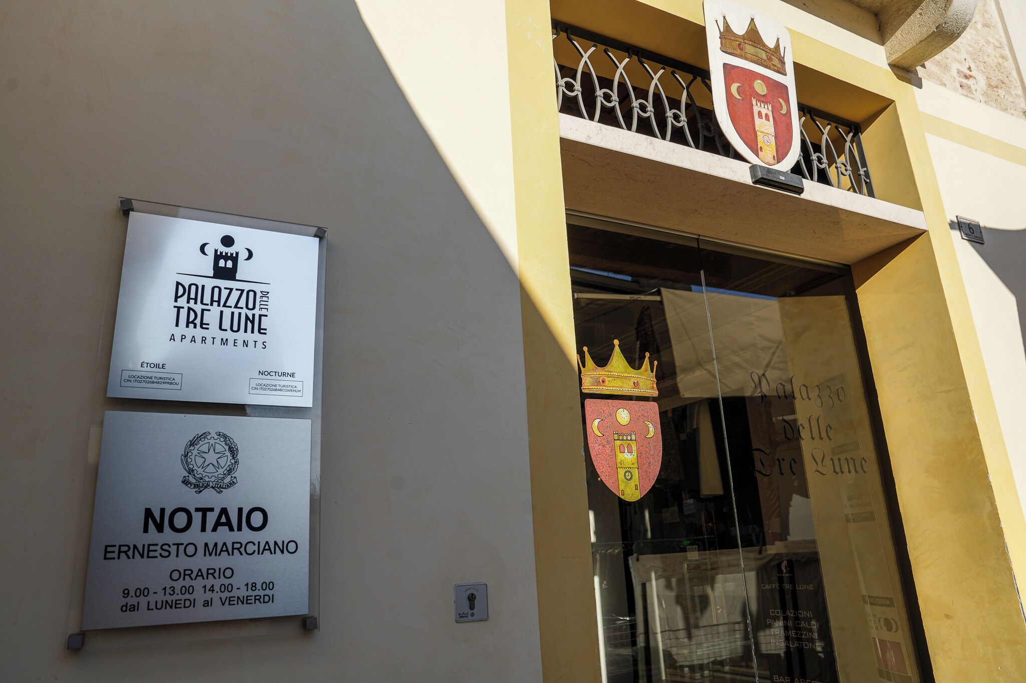 La entrada de un edificio con un cartel que dice 'Palazzo Tre Lune Apartments' y un cartel de 'Notaio Ernesto Marciano'.