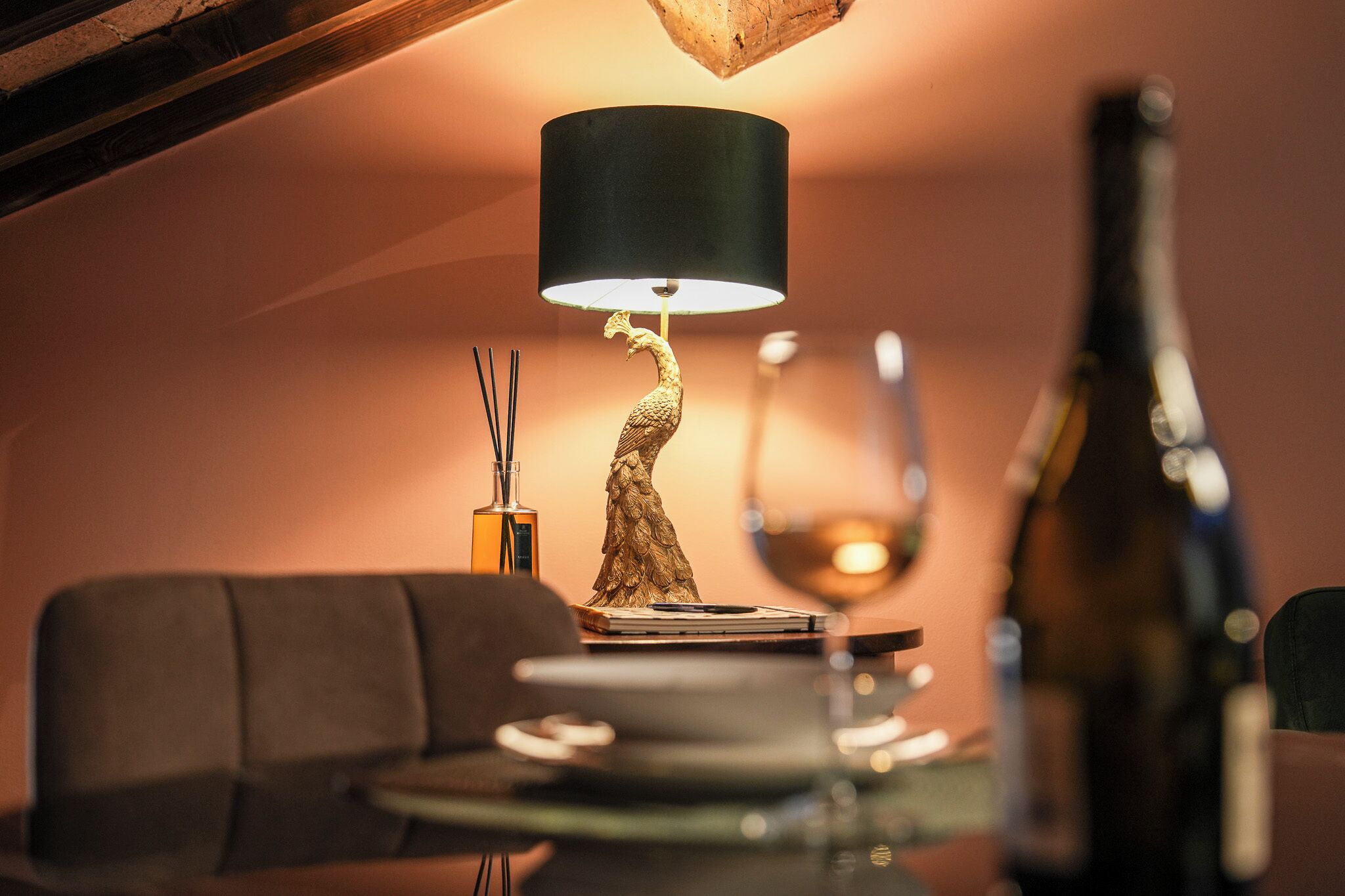 Une table à manger agrémentée d’une lampe décorative, d’un verre à vin et d’une bouteille.