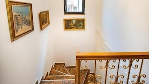 A staircase with stone steps, a chandelier, and framed pictures on the walls. - Nobilis Boutique Foisor (Bucharest)