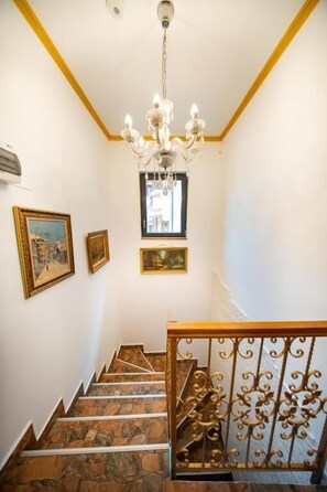 Eine Treppe mit Steinstufen, einer Kandelaberleuchte und gerahmten Bildern an den Wänden.