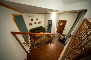 A staircase with a wooden handrail and a green cushioned sofa in the background.