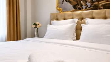 Habitación de hotel con una cama grande, ropa blanca, una toalla blanca enrollada, un cuadro en la pared y un equipo de aire acondicionado.