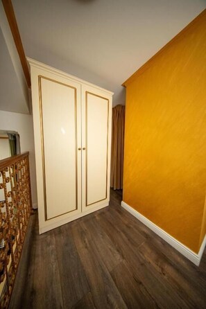 Ein Zimmer mit Holzboden, einem weißen Kleiderschrank und einer gelben Wand.